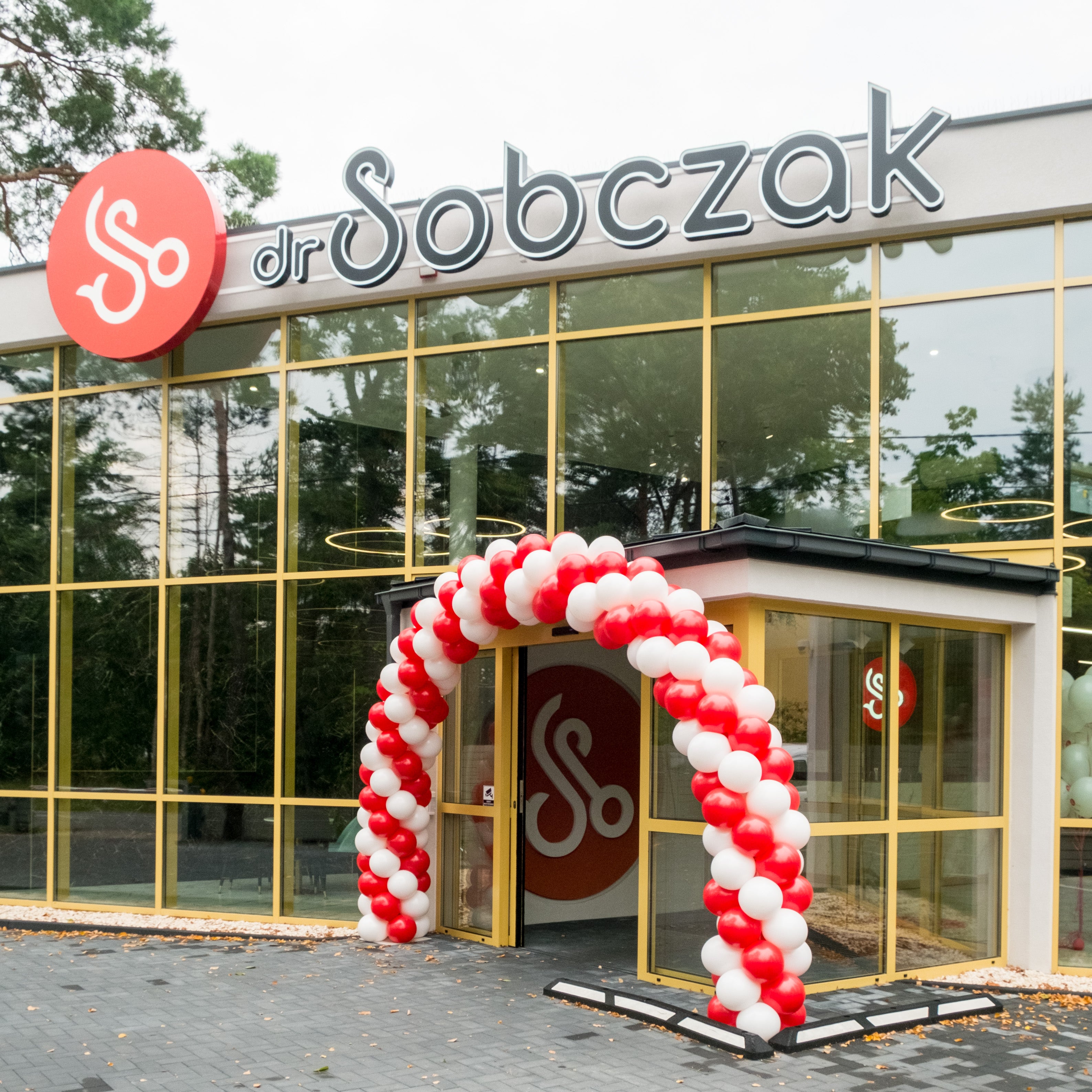 łuk z balonów przed wejściem do budynku kolory czerwony i biały