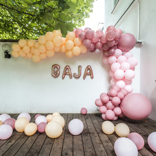 Pastelowa girlanda balonowa na baby shower dziewczynki w ogrodzie.